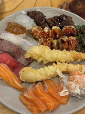 Çeşitli malzemeler ve canlı renklerle sanatsal olarak düzenlenmiş taze suşi çeşitleri. Bu geleneksel Japon yemeği bir deneyim için sirkeli pirinç, deniz ürünleri ve sebzeleri birleştirir..