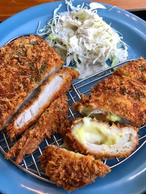 Erimiş peynirle doldurulmuş çıtır tonkatsu pirzolası, kıtır kıtır ve kremanın lezzetli bir karışımını oluşturuyor. Zengin ve altın kaplamalı rahatlatıcı bir yemek..