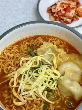 Yumuşak, lezzetli mandu köfteleriyle birlikte rahatlatıcı bir ramyun kasesi. Bu tatmin edici karışım, çiğnenmiş erişte, bol et suyu ve lezzetli hamur tatlısı sunar..