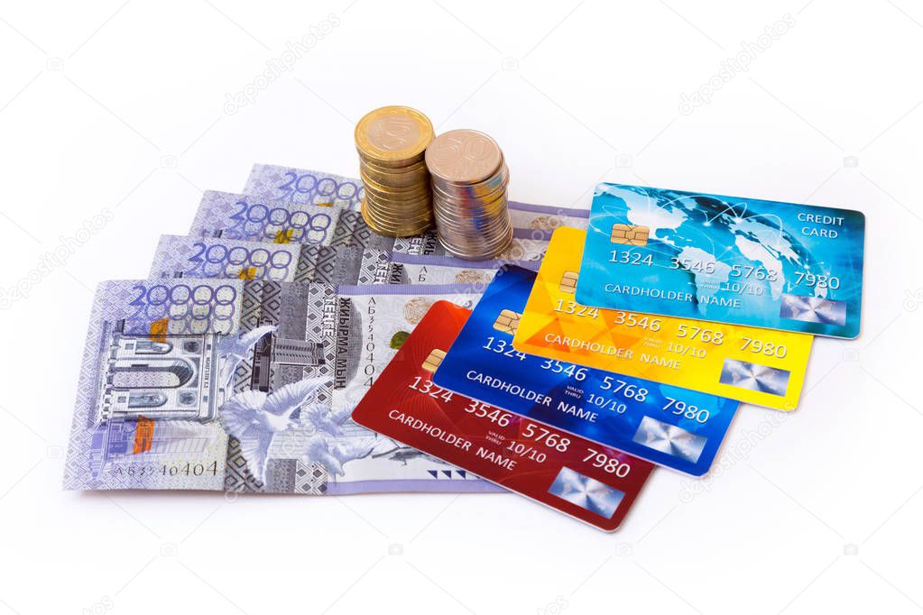 Closeup of a collection of kazakhstani tenge banknotes and coins and a set of colourful credit cards isolated on white background