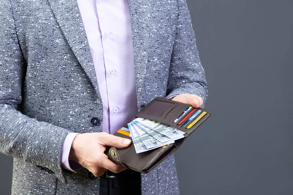 Uomo Giacca Grigia Con Mano Portafoglio Pelle Marrone Con Banconote Fotografia Stock