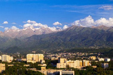 Gün batımından önce Almaty şehrinin üst kısmında karla kaplı dağlar. Yaz şehir manzarası