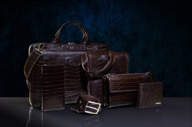 Kahverengi timsah derisi erkek aksesuarlar el çantası, çanta, el çantası, iki cüzdan ve koyu mavi arka planda kemer. Moda ve alışveriş konsepti