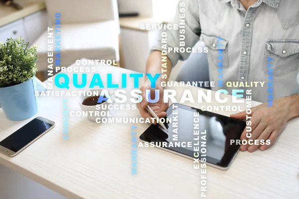 Kalite güvencesi kavramı sanal ekran üzerinde. İş kavramı. Kelime bulutu.