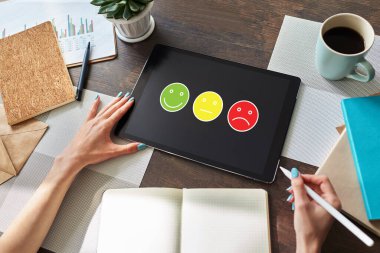 Renkli gülücükler. Müşteri memnuniyeti kontrolü cihaz ekranında. Hizmet ve kalite iyileştirme kavramı.