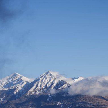 Champsaur Vadisi 'nde açık mavi bir kış gökyüzü altında görkemli kar kaplı Petite Autane ve Grande Autane dağlarının panoramik manzarası.