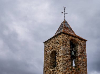 Tarihi Sant Climent d 'Estana Kilisesi' nin taş çan kulesi rüzgar gülü ile Katalonya, İspanya 'da karanlık ve bulutlu bir gökyüzüne kurulmuştur.