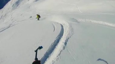 Taze kar kazıyan ve sıçrama tahtası atlayan snowboardcuyu takip ediyorum.