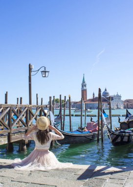 Gondol Venedik, İtalya ile Harbor taş duvarda oturan kız
