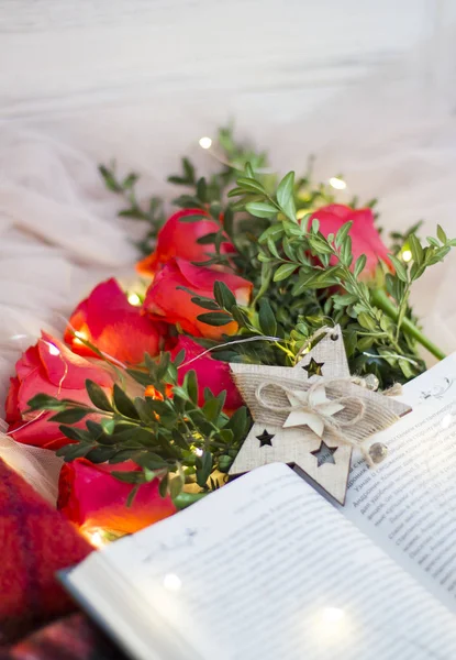 Composition of red roses with boxwood and book with garlands and red blanket