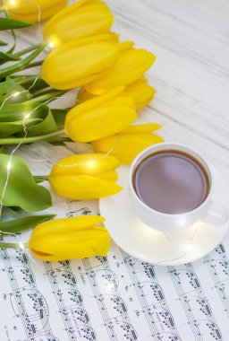 çelenk, kahve, kapuçino ve beyaz ahşap arka plan üzerinde notlar ile sarı lale