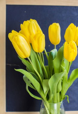 Bir tahta arka plan üzerinde sarı lale bir buket