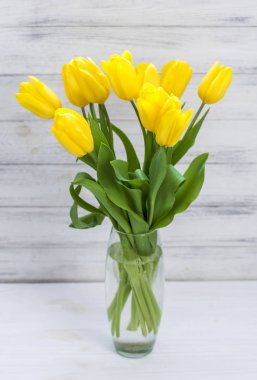 Beyaz ahşap tahta arka plan üzerinde bir vazo sarı lale buket