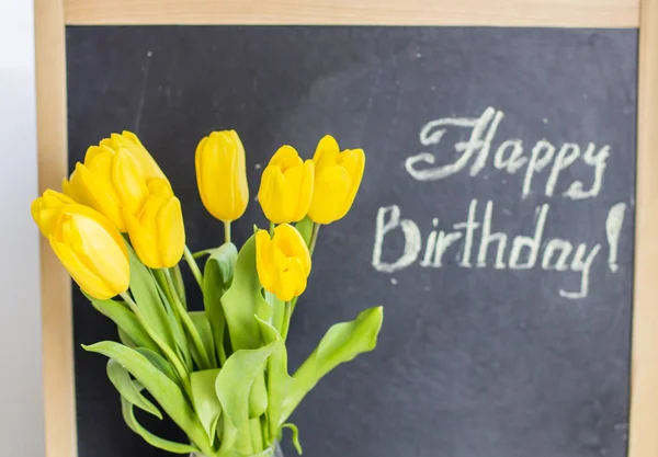 A bouquet of yellow tulips and the inscription in chalk \