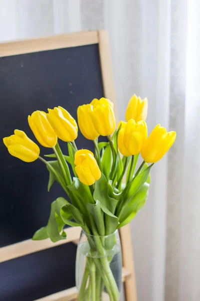 A bouquet of yellow tulips on a blackboard background