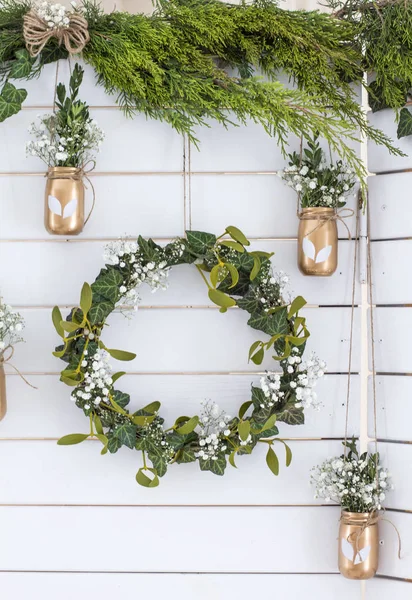 Spring decor. Easter decor. Photozone. A wreath of leaves on a wooden white background. Vase with flowers