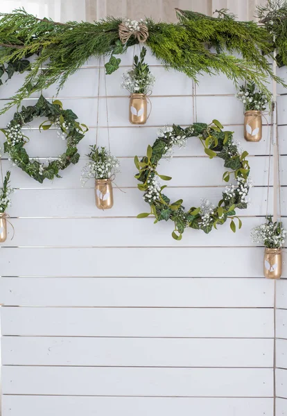 Spring decor. Easter decor. Photozone. A wreath of leaves on a wooden white background. Vase with flowers