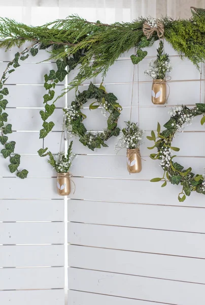 Spring decor. Easter decor. Photozone. A wreath of leaves on a wooden white background. Vase with flowers