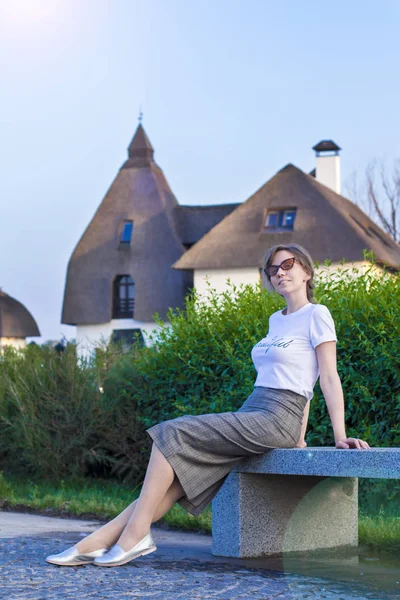 Güneş gözlüğü içinde İş kadını evlerin arka planda bankta oturan 