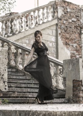 Terk edilmiş bir sarayın merdivenlerinde siyah bir gece elbisesi içinde güzel bir kız. Yara izi olan güzel bir kadın. Retro tarzında genç kız. Güzel Kadın
