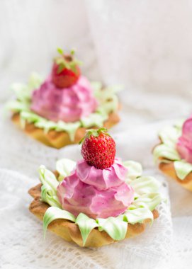 Çilekli, pembe ve açık kremalı kapkekler.