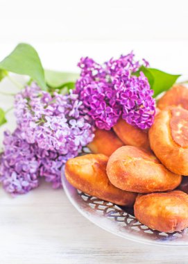 Piroshki - Rus usulü lahana dolgulu puf böreği ve bir buket leylak. Geleneksel Rus lahanası doldurulmuş hamur işi. Lahanalı yağsız turtalar. Lahanalı güzel ev yapımı kekler. 