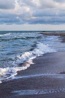 Deniz dalgaları, kumlu sahil ve bulutlar