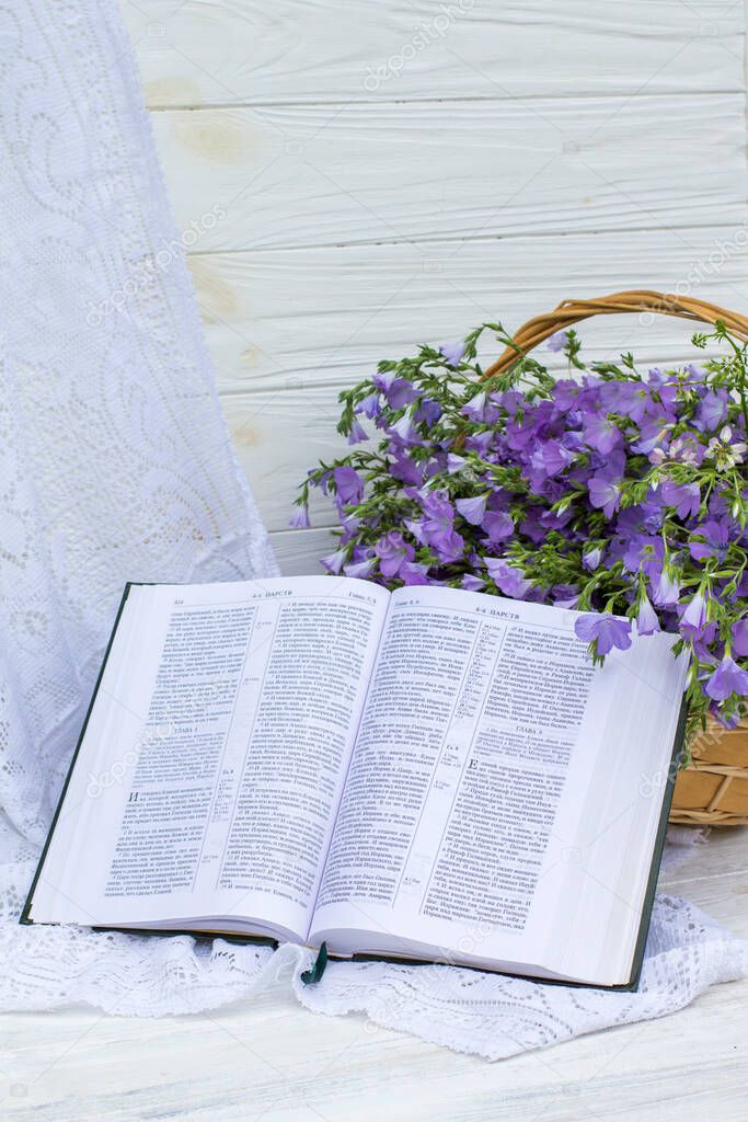 Open Bible and bouquet flax in wicker basket