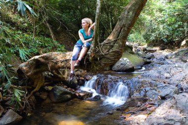 Yorgun kadın bir ağaç gövdesine oturur. Asya 'nın doğası.