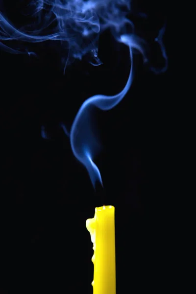The smoke rises above the extinguished candle. Close-up.