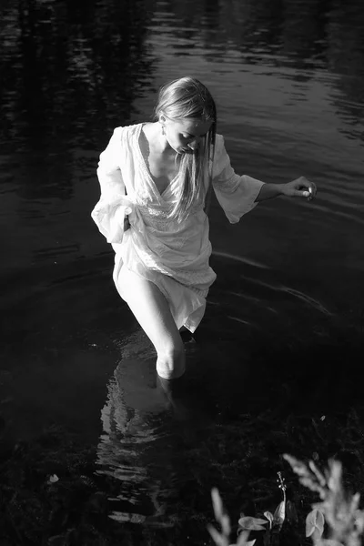 白いドレスで美しい若い女性は 水に歩いています 黒と白の写真 — ストック写真