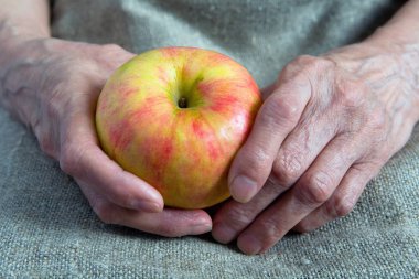 Yaşlı bir kadın elinde olgun bir elma. Gövde bölümü.