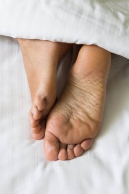 İnsan ayakları metrelik battaniyenin altından çıkıntı. Gövde bölümü.