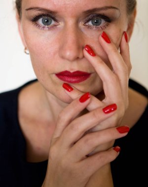 Güzel bir genç kadın yüzünü parmakları ile temas ediyor. Makyaj ve manikür.