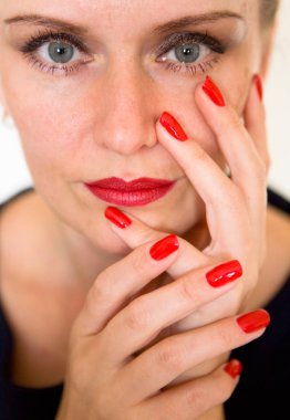 Güzel bir genç kadın yüzünü parmakları ile temas ediyor. Makyaj ve manikür.