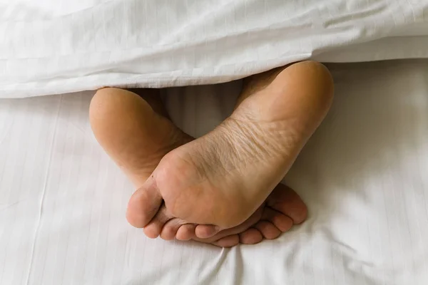 İnsan ayakları metrelik battaniyenin altından çıkıntı. Gövde bölümü.