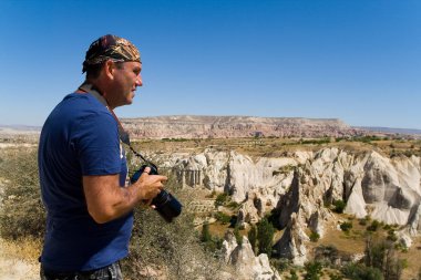 Dağ manzarasının arka planında kamera olan bir adam. 