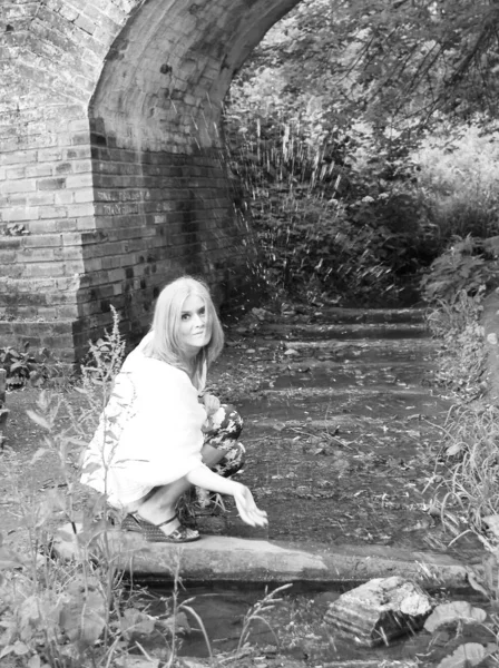 Hermosa joven mujer salpica el agua de un arroyo bajo un viejo — Foto de Stock