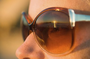 Denizde gün batımı güneşten gelen gözlüklere yansır.