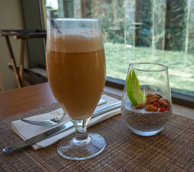 Sağlıklı kahvaltı: Bademli chia tohumu pudingi ve pencerenin yanındaki masada buzlu kahve.