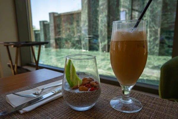 Sağlıklı kahvaltı: Bademli chia tohumu pudingi ve pencerenin yanındaki masada buzlu kahve.