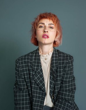 Dağınık kısa saç ve doğal makyaj ve yüz ve boyun studio, izole kareli takım elbiseyle poz dikiş hatları ile yaratıcı genç kafkas kadın kameraya bakarak portresi. Tasarım giyim moda kavramı