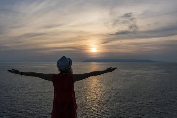 Open arms of a woman on the beach at sunset