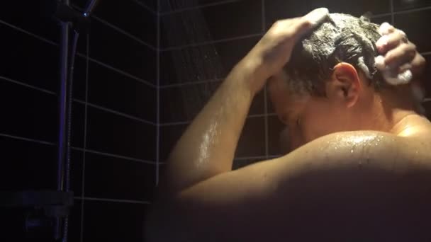 Jonge man wast zijn hoofd in de douche — Stockvideo
