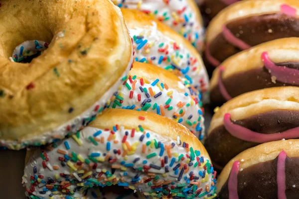 Deliciosos donuts com cobertura e polvilhas na prateleira da loja — Fotografia de Stock