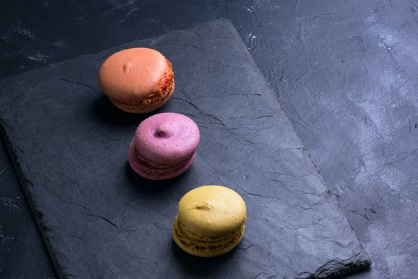 Foto en una llave oscura Macarrones dulces multicolores franceses —  Fotos de Stock