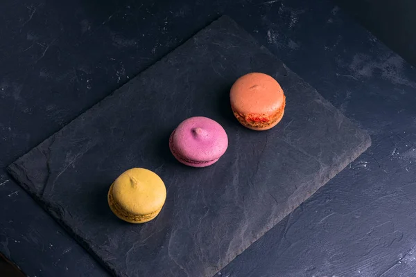 Foto en una llave oscura Macarrones dulces multicolores franceses —  Fotos de Stock