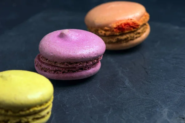 Foto en una llave oscura Macarrones dulces multicolores franceses —  Fotos de Stock