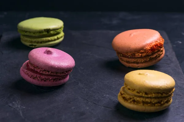Foto en una llave oscura Macarrones dulces multicolores franceses —  Fotos de Stock