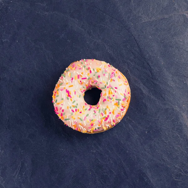 Donut fresco com coberturas em um fundo escuro — Fotografia de Stock